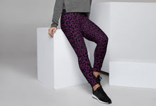 Load image into Gallery viewer, Woman wearing purple leopard print leggings and a gray sweater sitting on a white cube.