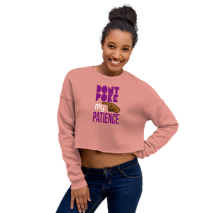 Woman wearing a mauve cropped sweatshirt with text, 'DON"T POKE MY PATIENCE' and graphic hand design.